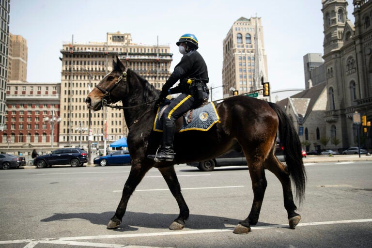 A mounted police officer patrols while wearing a protective face mask as a precaution against the coronavirus in Philadelphia, Friday, April 17, 2020. (AP Photo/Matt Rourke)