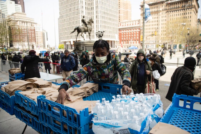 Volunteer Diamon Logan with Broad Street Ministry distributes food as part of a new initiative called Step Up to the Plate, outside City Hall in Philadelphia, Friday, April 17, 2020. The program aims to help those with food insecurity and is a partnership of Broad Street Ministry, Prevention Point Philadelphia, and Project HOME, with the City of Philadelphia. (AP Photo/Matt Rourke)