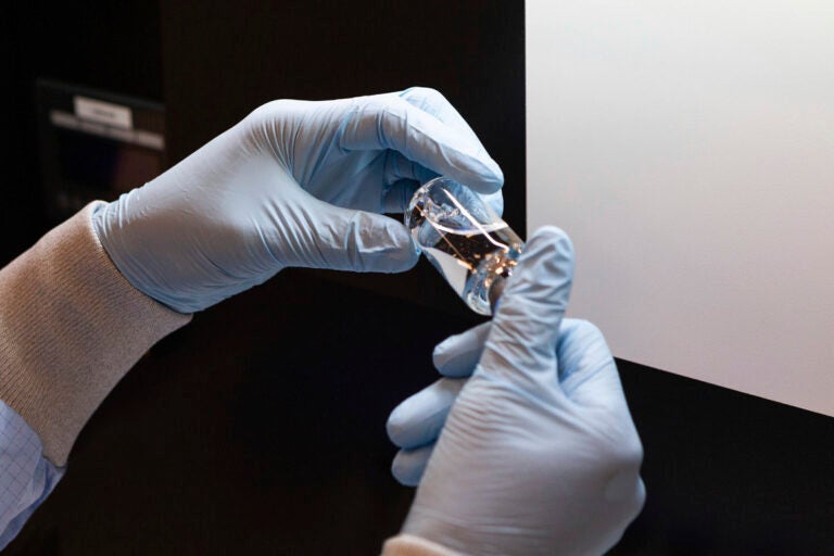 In this March 2020 photo provided by Gilead Sciences, a vial of the investigational drug remdesivir is visually inspected at a Gilead manufacturing site in the United States. (Gilead Sciences via AP)