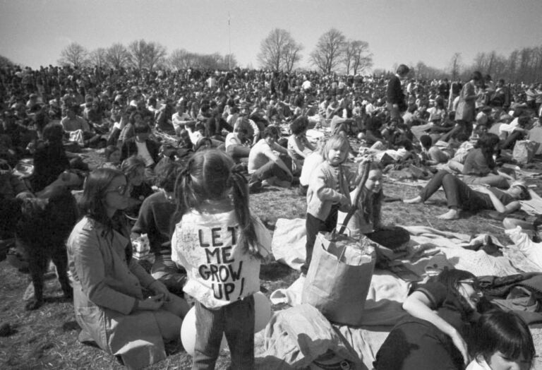 A black-and-white photo shows people gathered in a park.