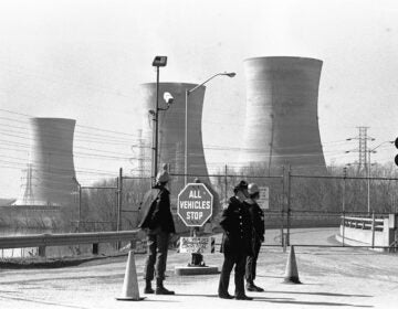 FILE - In this Wednesday, March 28, 1979 file photo, a Pennsylvania state police officer and plant security guards stand outside the closed front gate to the Three Mile Island nuclear power plant near Harrisburg, Pa. after the plant was shut down following a partial meltdown. (AP Photo/Paul Vathis)