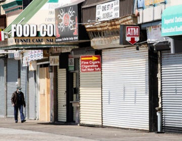 Person wearing masks walks by shuttered New Jersey businesses