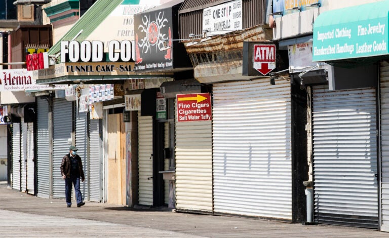 Person wearing masks walks by shuttered New Jersey businesses