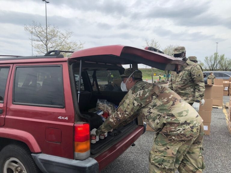 Brian Turner of the Delaware National Guard places food in a trunk during Monday's giveaway. (Cris Barrish/WHYY)