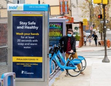 A rider stands next to an Indego station. (Indego/City of Philadelphia)