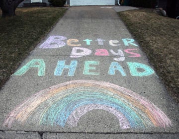 A chalk message and rainbow adorn a driveway with a positive message in the fight against the coronavirus at a home on Wednesday, April 1, 2020. (AP Photo/Jim Mone)