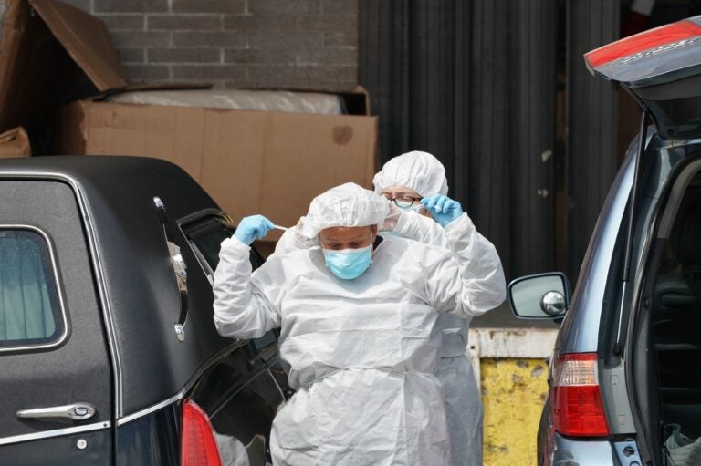 Funeral home workers put on protective gear to retrieve a body from a refrigerated truck outside a Brooklyn hospital in early April. As of Sunday, the U.S. reported the most coronavirus deaths in the world, surpassing Italy. (Bryan R. Smith/AFP via Getty Images)