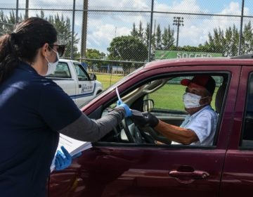 A man collects unemployment forms at a drive-through collection point outside of a library in Hialeah, Fla., on Wednesday. (Chandan Khanna/AFP via Getty Images)