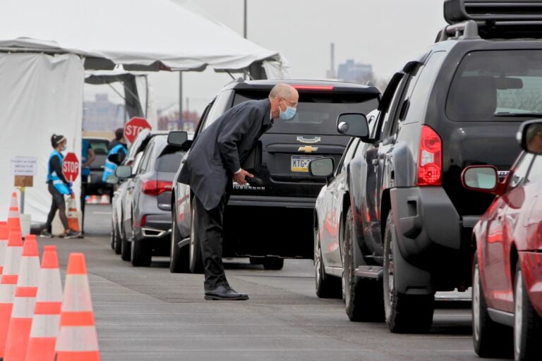 Philadelphia Health Commissioner Thomas Farley walks among cars lined up for coronavirus testing at Citizens Bank Park, pausing to speak with the occupants of each car. (Emma Lee/WHYY)