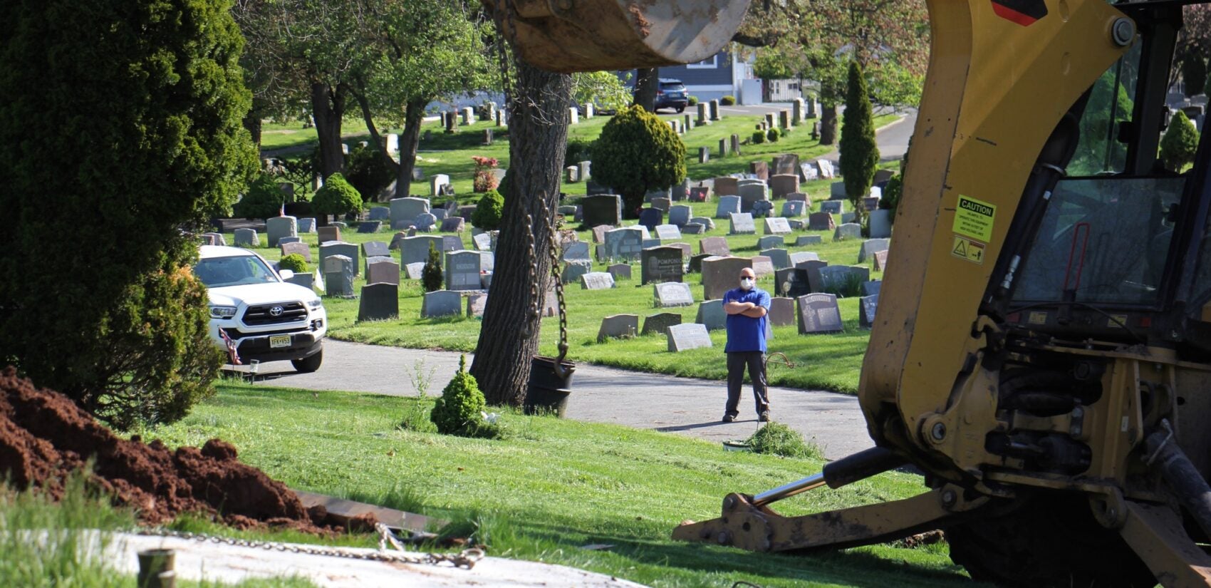 Jeff Dodgson, who oversees the grounds crew at Glendale Cemetery in Bloomfield, N.J., watches as a grave is prepared. (Emma Lee/WHYY)