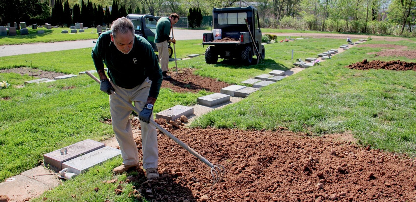 Cemetery workers Pete Sparaco (left) and Frank Mangua tend to fresh graves at Glendale Cemetery in Bloomfield, N.J. 'It's like a war zone,' Sparaco said of the many recent burials. (Emma Lee/WHYY)