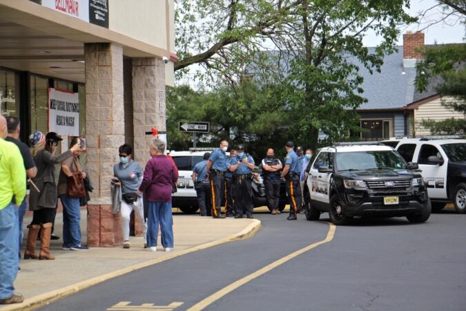 Police watch protesters outside Atilis Gym in Bellmawr, N.J. A crowd of about 30 gathered in the parking lot to support the gym's owners, who had opened despite the governor's order that recreational and entertainment businesses remain closed to slow the spread of coronavirus. (Emma Lee/WHYY)