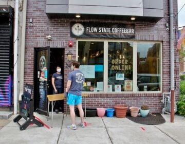 A customer picks up jugs of coffee at Flow State Coffeebar in Fishtown. (Emma Lee/WHYY)