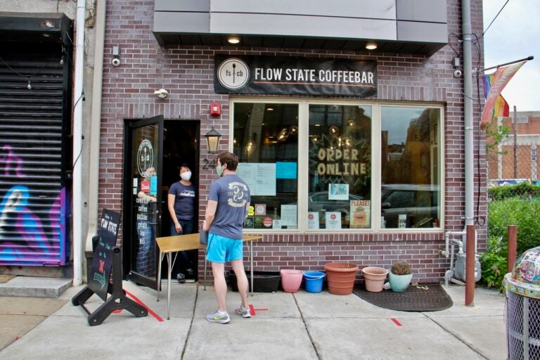 A customer picks up jugs of coffee at Flow State Coffeebar in Fishtown. (Emma Lee/WHYY)