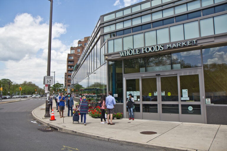 An employee directs people into the store at the Whole Foods grocery in Philadelphia’s Fairmount neighborhood. (Kimberly Paynter/WHYY)
