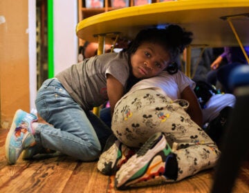 Justice Buress, 4, hides under a table while demonstrating a drill at Little Explorers Learning Center in St. Louis. Tess Trice, head of the day care program, carries out monthly drills to train the children to get on the floor when they hear gunfire.