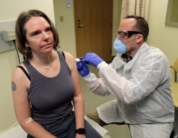 Jennifer Haller (left) is given the first shot in the first-stage safety study clinical trial of a potential vaccine for the COVID-19 coronavirus by a pharmacist, Monday, March 16, 2020, at the Kaiser Permanente Washington Health Research Institute in Seattle. (AP Photo/Ted S. Warren)