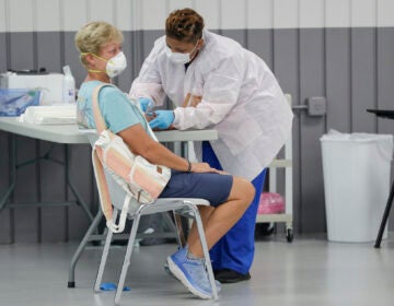 Health worker Eboni Smith, right, draws blood from a patient during a COVID-19 antibody test at the Volusia County Fairgrounds Tuesday, May 5, 2020, in DeLand, Fla. (AP Photo/John Raoux)