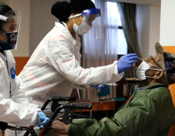 Willie Johnson, right, a resident of senior housing, gets tested for COVID-19 in Paterson, N.J., Friday, May 8, 2020. (AP Photo/Seth Wenig)