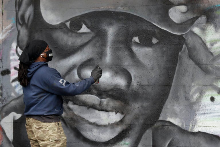 Artist Theo Ponchaveli paints a mural of the likeness of Ahmaud Arbery in Dallas, Friday, May 8, 2020. (AP Photo/Tony Gutierrez)