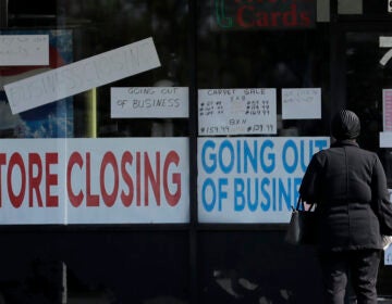 A woman looks at signs at a store closed due to COVID-19. (AP Photo/Nam Y. Huh)