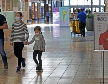 Shoppers walks past a sign encouraging masks at SouthPark Mall, Wednesday, May 13, 2020, in Strongsville, Ohio. (AP Photo/Tony Dejak)