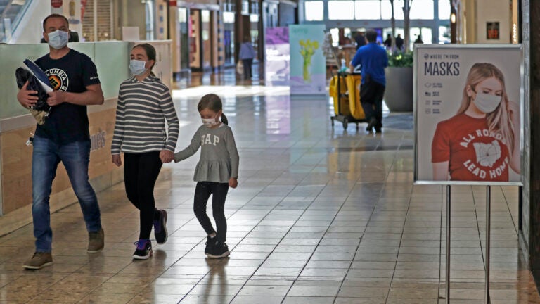 Shoppers walks past a sign encouraging masks at SouthPark Mall, Wednesday, May 13, 2020, in Strongsville, Ohio. (AP Photo/Tony Dejak)