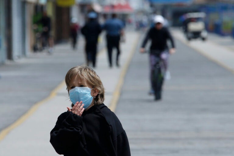 A boy adjusts his mask as he walks down the boardwalk, Thursday, May 21, 2020 in Wildwood, N.J. (AP Photo/Matt Slocum)