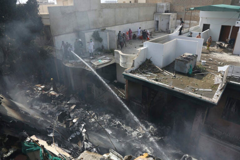 Fire brigade staff try to put out fire caused by plane crash in Karachi, Pakistan, Friday, May 22, 2020. (AP Photo/Fareed Khan)