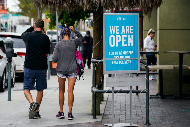 Customers walk past an open sign at Rubio's Coastal Grill