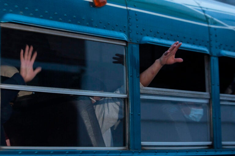 Guatemalans deported from the U.S., wave from a bus.