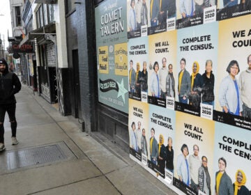 People walk past posters encouraging participation in the 2020 census in April in Seattle. A group of House Democrats have introduced a bill that would grant the U.S. Census Bureau's request to delay major deadlines for delivering results of the count because of the pandemic. (Ted S. Warren/AP Photo)