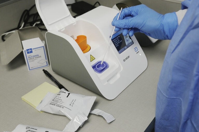 A lab technician dips a sample into the Abbott Laboratories ID Now testing machine at the Detroit Health Center on April 10, 2020. (Carlos Osorio/AP Photo)
