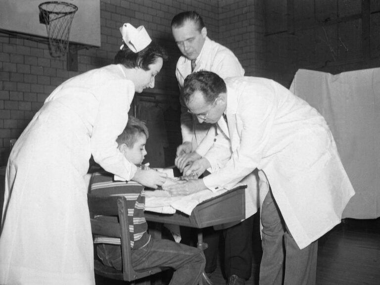 Dr. Jonas Salk, the scientist who created the polio vaccine, administers an injection to an unidentified boy at Arsenal Elementary School in Pittsburgh, Pa., in 1954. (AP)