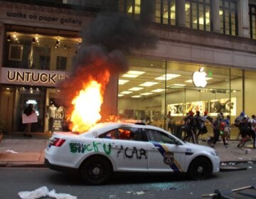A police car burns outside a looted Apple store in Center City.
