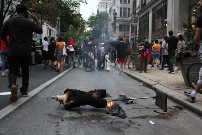 A mannequin burns in the street as looters make their way through Center City.