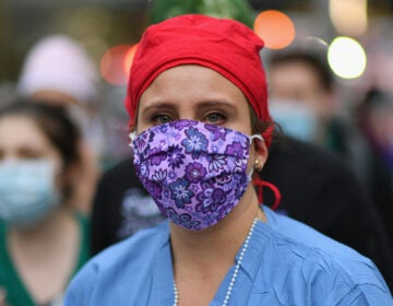 A health care worker looks on as people cheer to show their gratitude to medical staff outside NYU Langone Health hospital in New York City last month. (Angela Weiss/AFP via Getty Images)