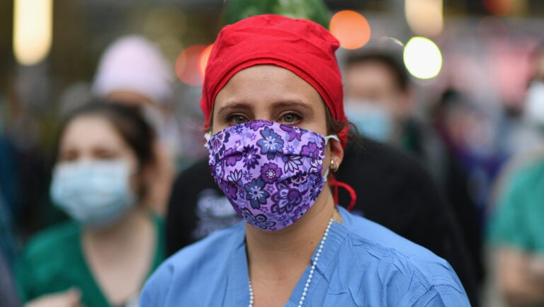 A health care worker looks on as people cheer to show their gratitude to medical staff outside NYU Langone Health hospital in New York City last month. (Angela Weiss/AFP via Getty Images)