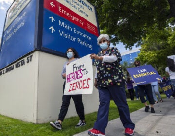 Health care workers hold a placard that says From Heroes to Zeroes during a protest