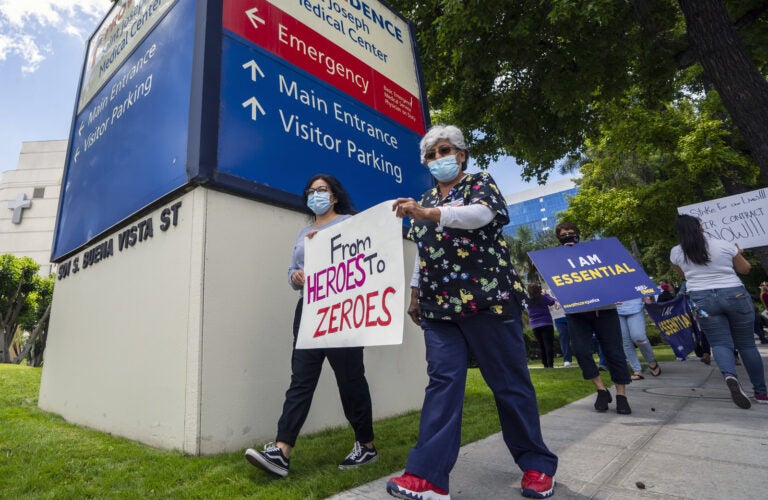 gettyimages-1214144507_custom-45ffa867517f80adf2f60bd686f16c47232eae66-s1600-c85 Health care workers hold a placard that says From Heroes to Zeroes during a protest