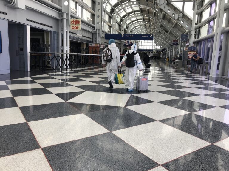 A couple dressed in protective gear walks through Chicago's O'Hare International Airport