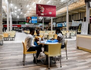 People eat in a deserted food court inside a mall west of Fort Lauderdale, Fla., Monday. U.S. states have been easing restrictions on businesses ahead of Memorial Day, the traditional start of the summer vacation and outdoor season. (Chandan Khanna/AFP via Getty Images)