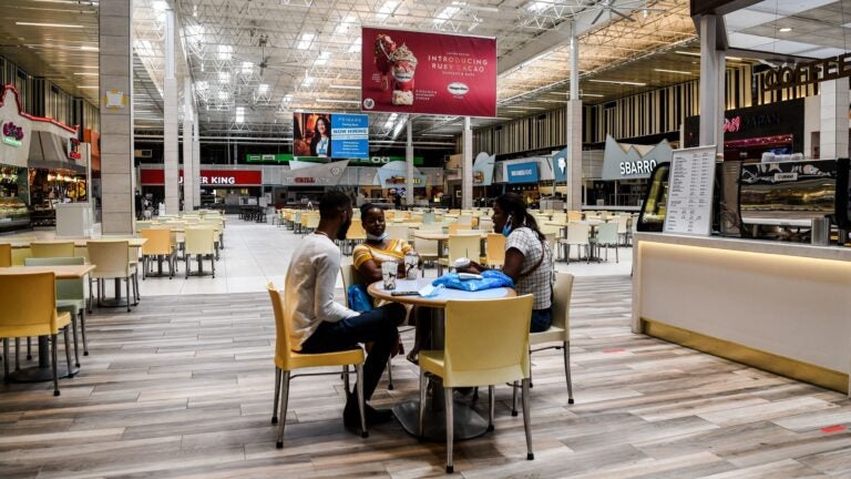 People eat in a deserted food court inside a mall west of Fort Lauderdale, Fla., Monday. U.S. states have been easing restrictions on businesses ahead of Memorial Day, the traditional start of the summer vacation and outdoor season. (Chandan Khanna/AFP via Getty Images)