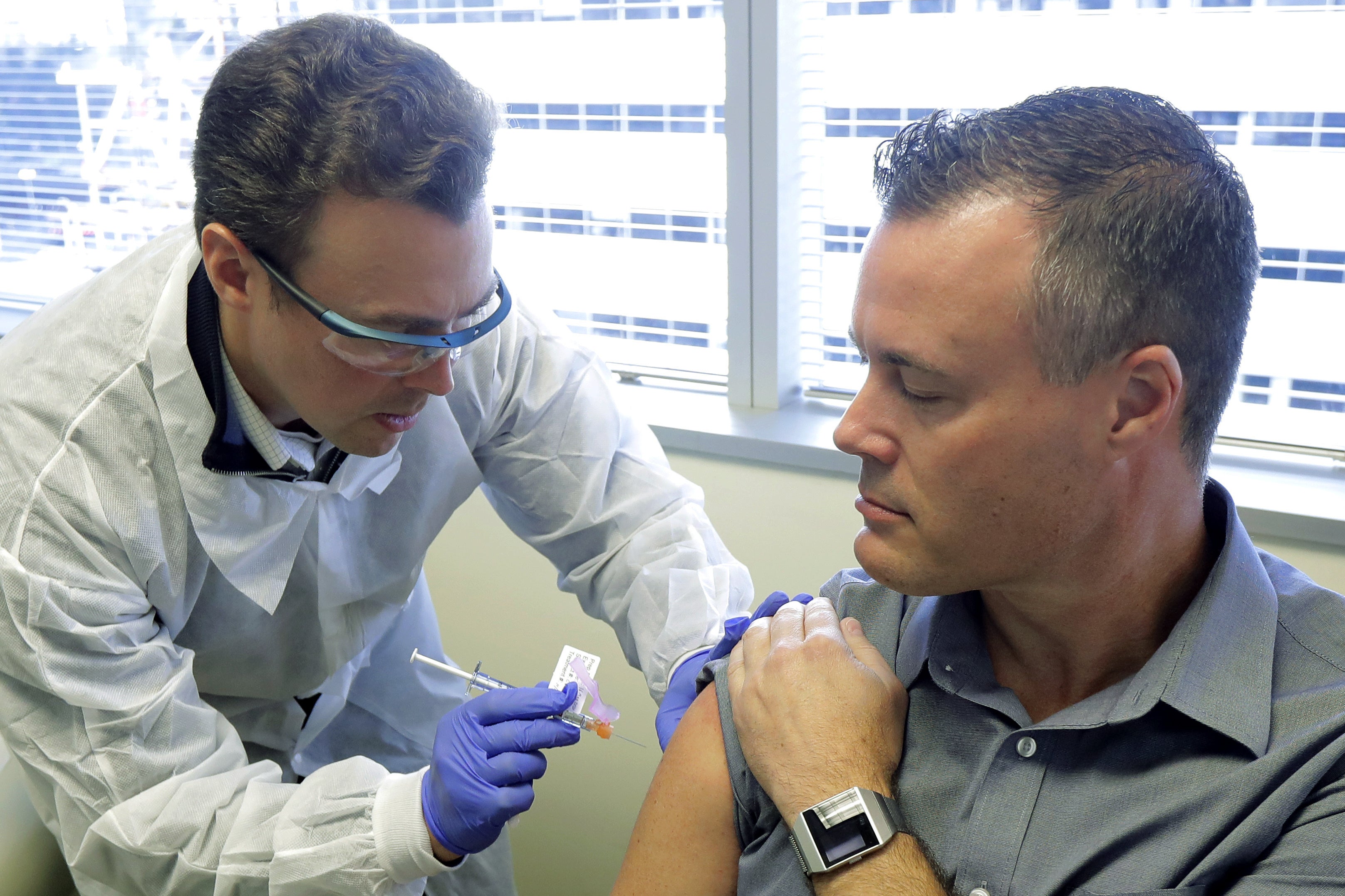 Pharmacist Michael Witte, left, gives Neal Browning a shot in the first-stage study of a potential coronavirus vaccine