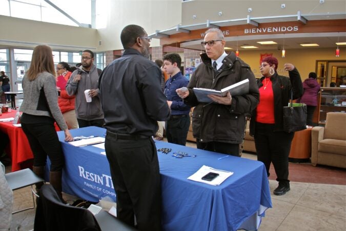 Job seekers line up at the ResinTech table during a job fair