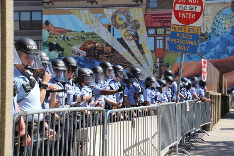 Philadelphia police protect the entrance to police headquarters on 8th Street as protesters march by on Saturday, May 30, 2020. (Emma Lee/WHYY)