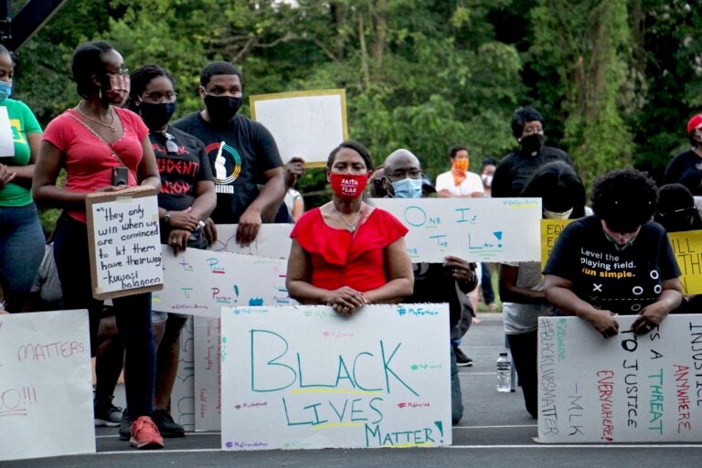 Protesters kneel for 8 minutes and 46 seconds in remembrance of George Floyd during a Black Lives Matter rally at Linconia Park in Bensalem, Pa. Floyd was killed in Minneapolis police custody by an officer who kneeled on his neck, sparking protests in cities and towns across the country. (Emma Lee/WHYY)