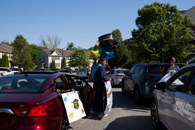 Bryson accepts balloons and a sign from a family member who attended his drive by graduation party on June 9, 2020. (Rachel Wisniewski for Keystone Crossroads)