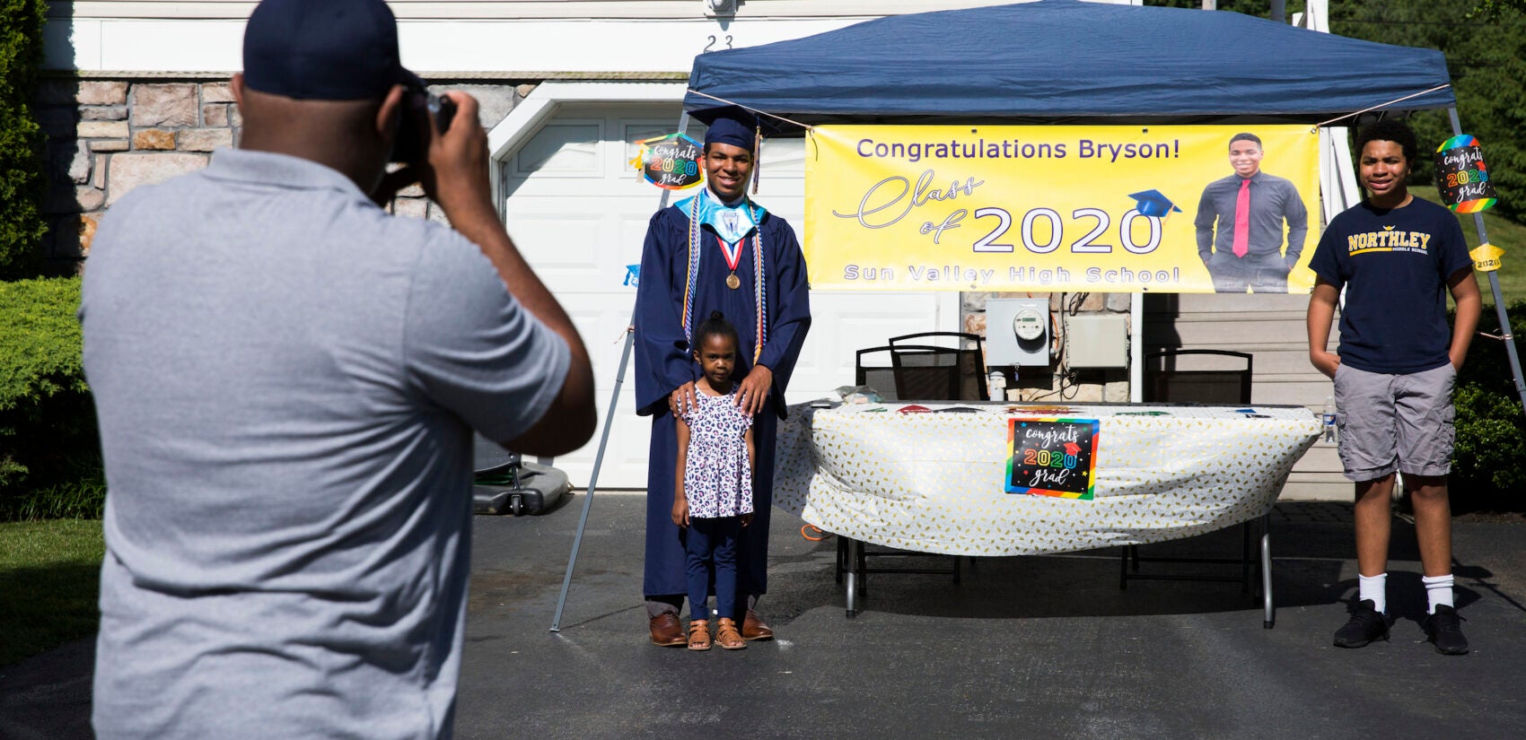 Gregory Eldridge takes a photo of his children (from left) Bryson, Kennedy, and Blaise in the driveway of their home on June 9, 2020, Bryson's graduation day. (Rachel Wisniewski for Keystone Crossroads)