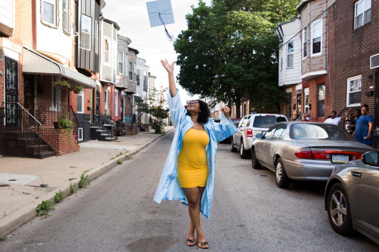 Aliah Harris, 18, throws her graduation cap in celebration on her dad's South Philly block on June 10, 2020. (Rachel Wisniewski for WHYY)